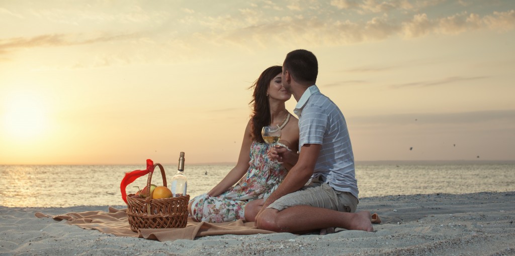 Couple On Beach With Luxury Wine Picnic during beautiful sunset.Honeymoon Cabo