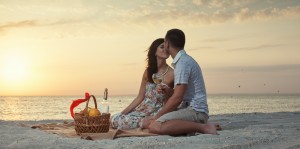 Couple On Beach With Luxury Wine Picnic during beautiful sunset.Honeymoon Cabo