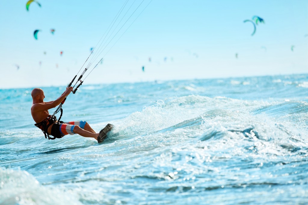 Kiteboarding, Kitesurfing. Water Sports. Professional Kite Surfer In Action On Waves In Ocean. Extreme Sport. Healthy Active Lifestyle. Hobby. Recreational Sporting Activity. Summer Fun, Adventure. Barbados Kitesurfing