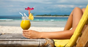 Woman holding a fruit cocktail on a tropical beach. Fabulous Caribbean Beach Bars