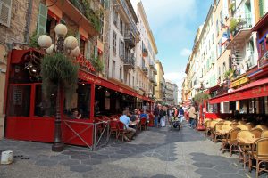 Nice, France, Narrow pedestrian street in Old Town of Nice, France with sidewalk cafes, souvenir shops and tourists walking around. Foodie Destinations Cote D'Azur