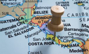 close up of a map with Costa Rica in focus and a pin marking the spot. book plane costa rica
