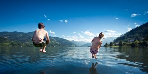 kids jumping into blue lake on summer day. Courchevel Summer Activities