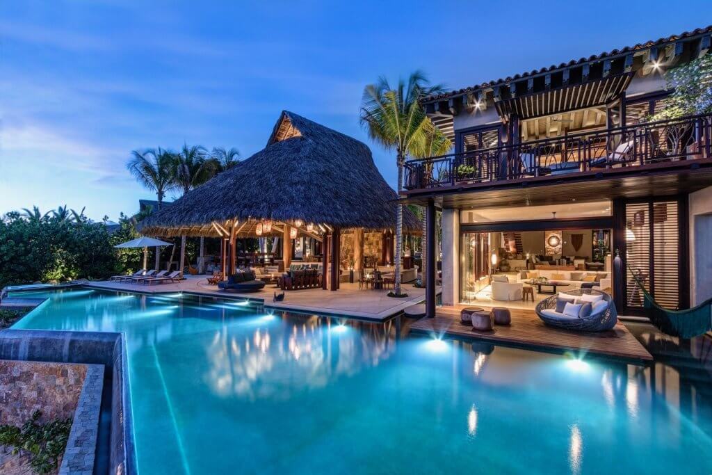 Punta Mita dining setting at Casa Koko with illuminated pool, palapa lounge and tropical evening views