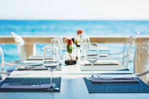 Dining Spots in Anguilla. Beach restaurant with sea view, table with empty wine glasses.