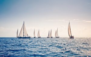 Nine sailing ship yachts with white sails in a row. BVI Spring Regatta