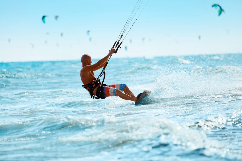 Kiteboarding, Kitesurfing. Water Sports. Professional Kite Surfer In Action On Waves In Ocean. Extreme Sport. Healthy Active Lifestyle. Hobby. Recreational Sporting Activity. Summer Fun, Adventure. Caribbean Watersports