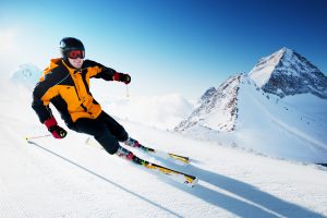 Skier in mountains, prepared piste and sunny day. Affordable places to ski