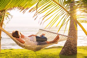 Romantic couple relaxing in tropical hammock at sunset. Affordable vacations for couples