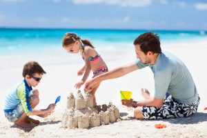 Father and kids making sand castle at tropical beach. Best family beach vacation