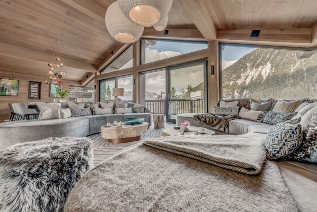 Chalet Bacchus living room with wood ceilings, full alpine views, and layered designer textiles in Courchevel.