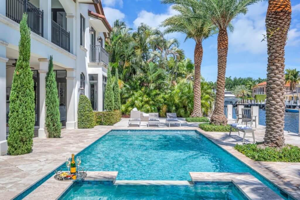 Florida luxury home with pool, palm trees, and canal view, showcasing classic outdoor elegance and coastal design.