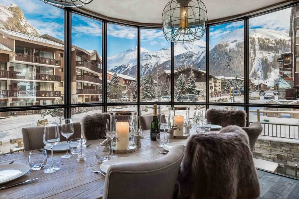 La Canadienne 2 chalet dining room with candles, wine, and panoramic mountain views in the French Alps ski resort.