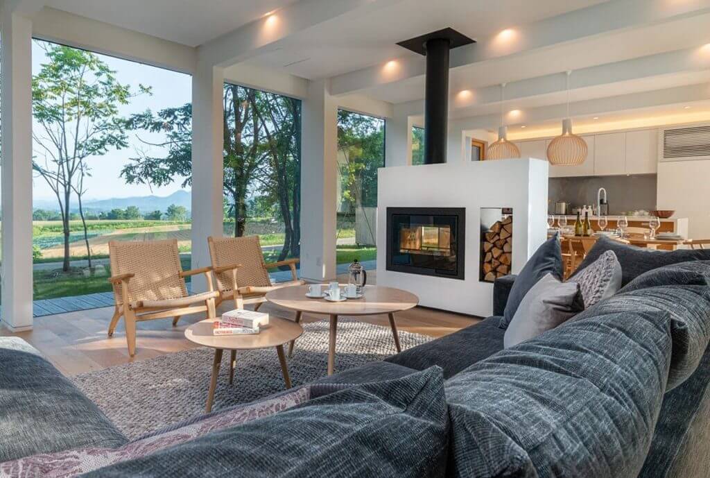 Chalet Yukihyo living room with fireplace, large windows, and dining area, part of Isle Blue’s luxury villas in Japan.