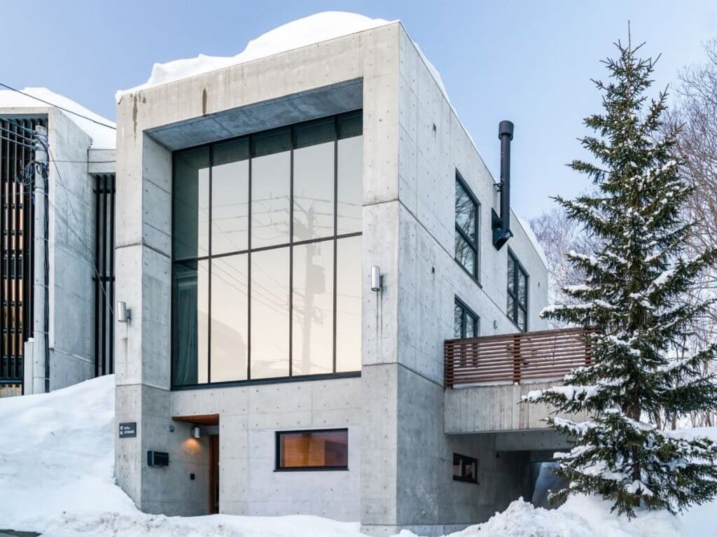 Modern luxury chalet surrounded by snowy pines near Niseko ski resort, Kita Kitsune, one of the top 7 luxury Niseko chalets.