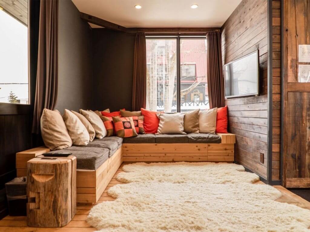 Cozy lounge with soft seating, wood walls, and warm lighting inside Momiji Lodge, a top luxury Niseko chalet.
