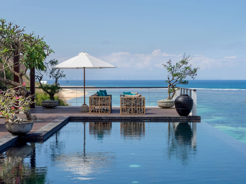 Luxury infinity pool at Villa Cliff Nusa Dua in Bali, surrounded by palm trees and oceanfront views.
