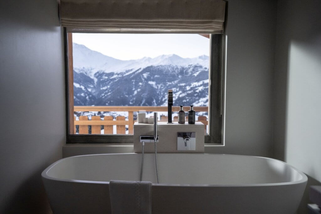 Freestanding bathtub with mountain view at No. 14 Verbier, a Luxury Ski Chalet in Switzerland offering serene alpine luxury.