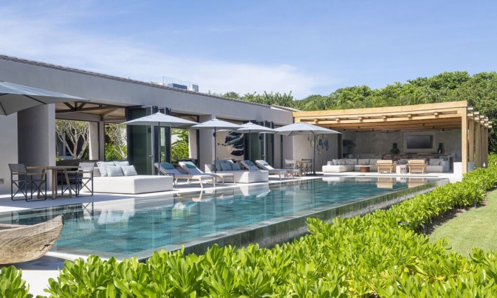 Casa Bella Vils in Punta Mita with a long infiniy pool, shaded loungers, and open-air living and dining spaces.
