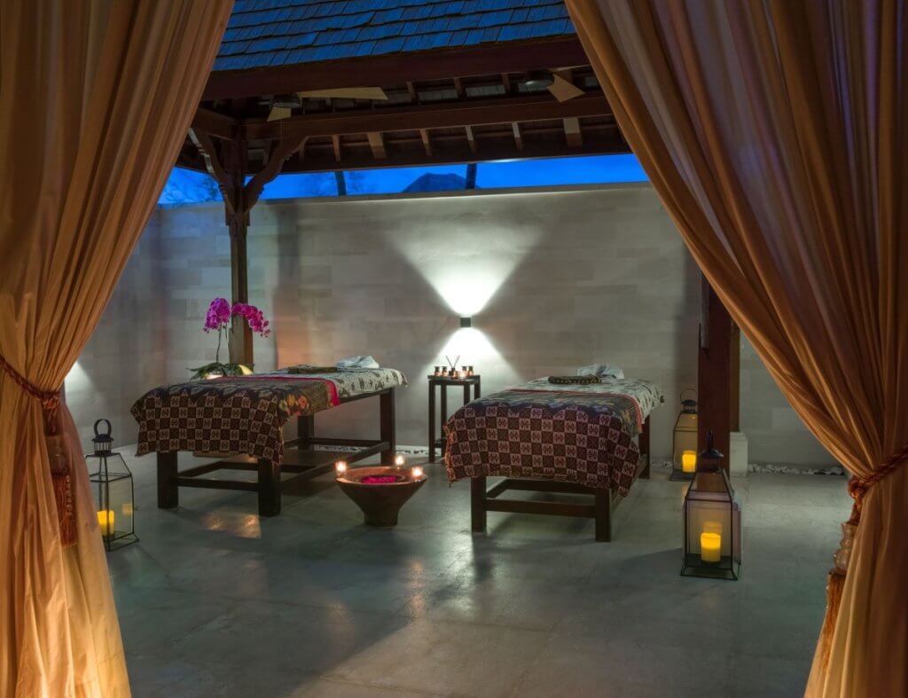 Villa living experiences at Villa Ambra with two spa beds, lanterns, orchids, and candlelit decor in an open-air wellness pavilion.