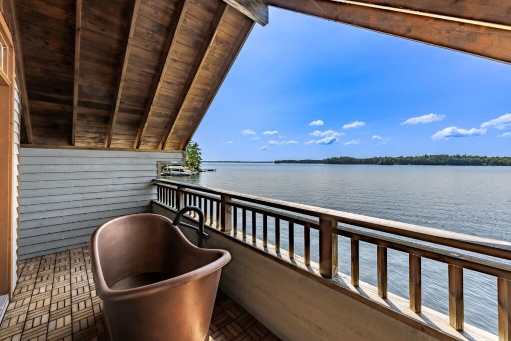 Copper bathtub on a private balcony overlooking a serene lake, perfect for Muskoka luxury villas.