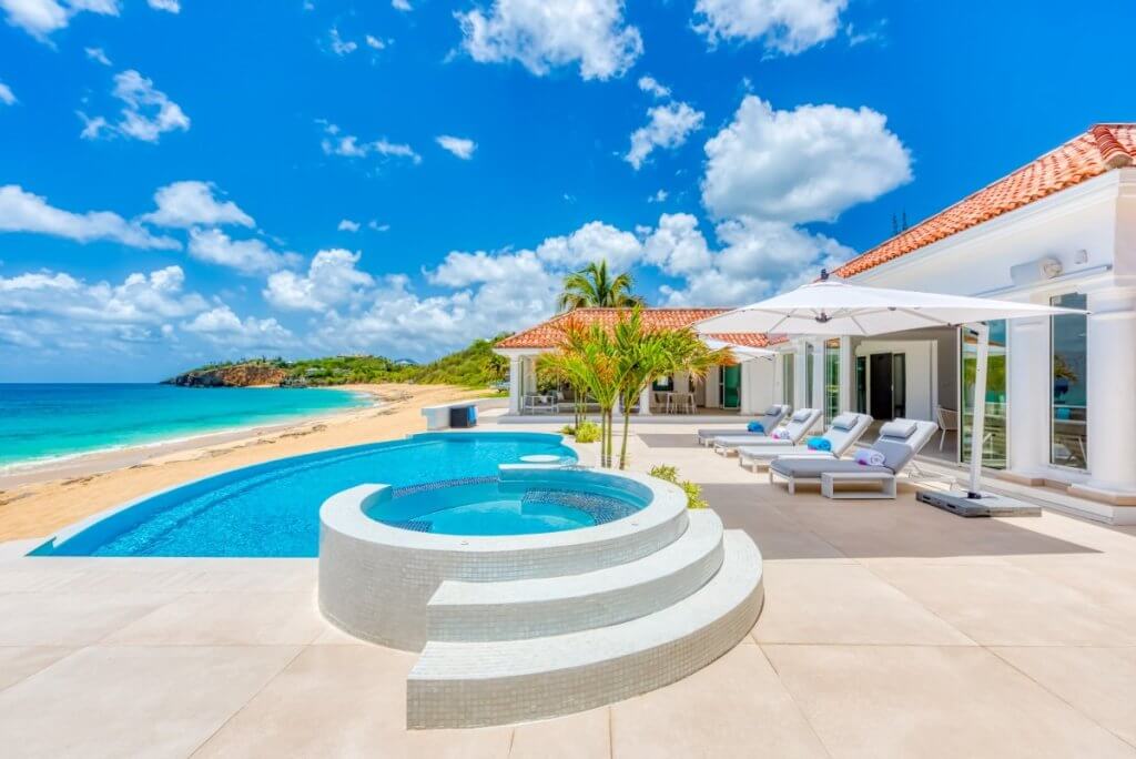 Villa Carisa in St Martin with beachfront pool, circular hot tub, ocean views, and luxury villa amenities under a bright sky.
