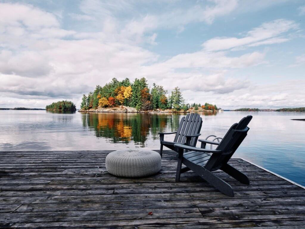 Two Adirondack chairs on a lakeside dock at Driftwood Island Retreat, a Muskoka luxury villa in Toronto.