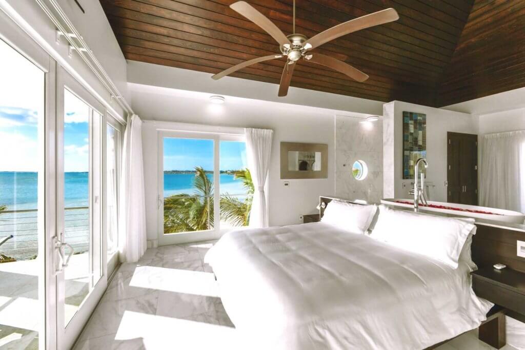 Luxurious bedroom at Villa Positano Turks & Caicos with a bathtub and bed overlooking the ocean, ideal for honeymoon stays.