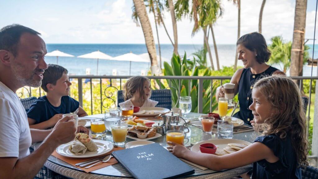 Family enjoys breakfast with ocean views at Pelican House, Antigua, where luxury meets tropical serenity.