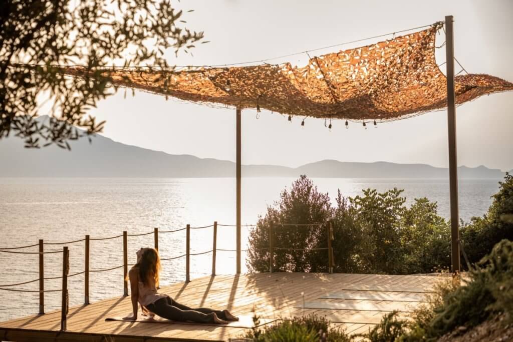 Woman practicing yoga at Bliss House, Crete, with serene sea views, ideal for luxury wellness villa vacations.