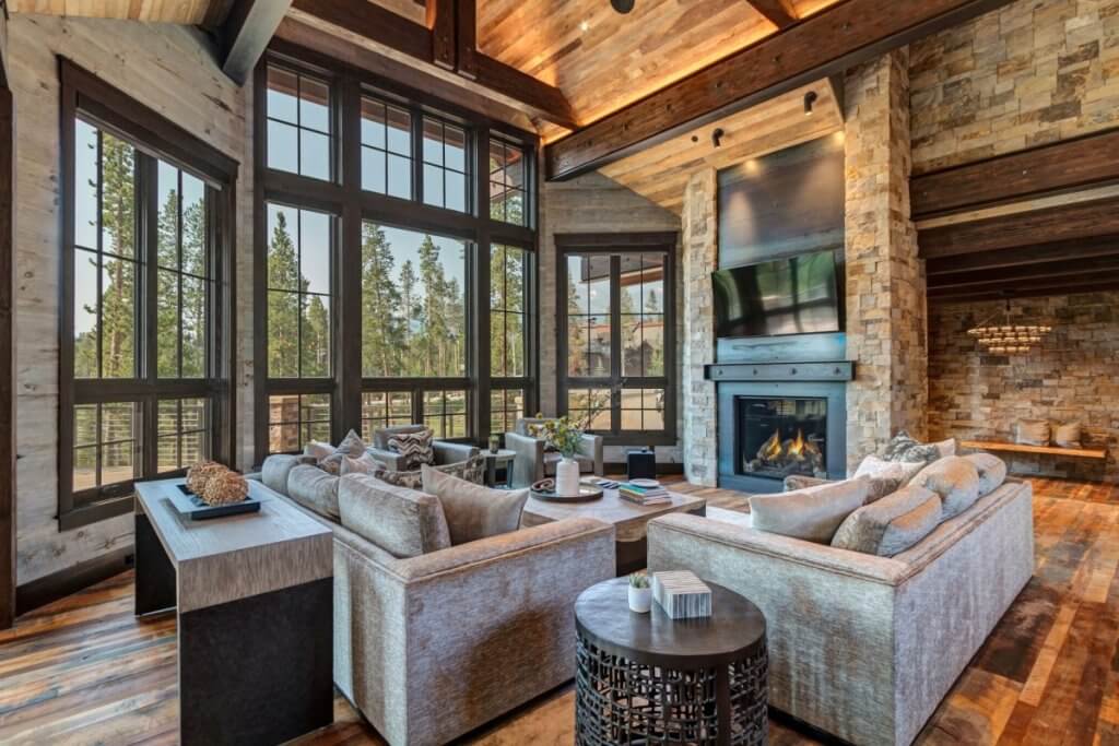 Rustic-modern living room at Peerless Haven villa with forest views, stone fireplace, and plush seating