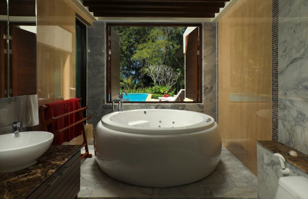 Bathroom with round jacuzzi, marble finishes, and tropical garden view at Ataman villa
