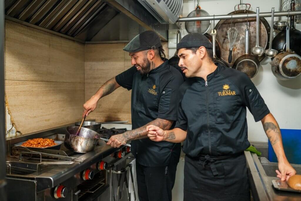Two chefs preparing gourmet dishes in the fully equipped kitchen at TuluMar, Tulum villa.