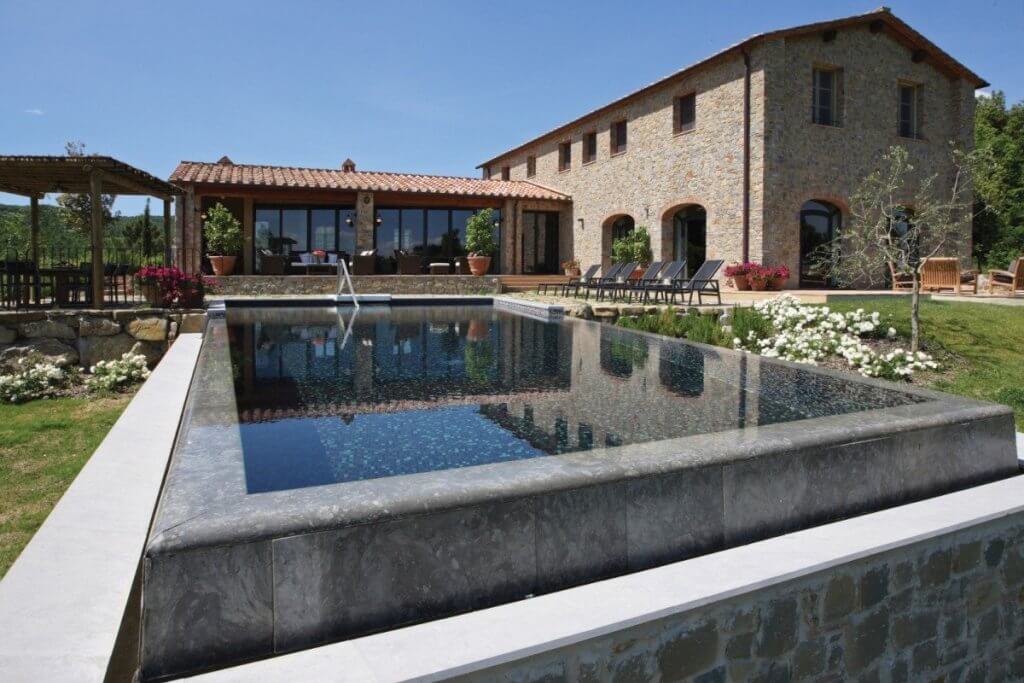 Poggio Corona’s stone exterior and reflective infinity pool create a serene Tuscan setting ideal  luxury escape.