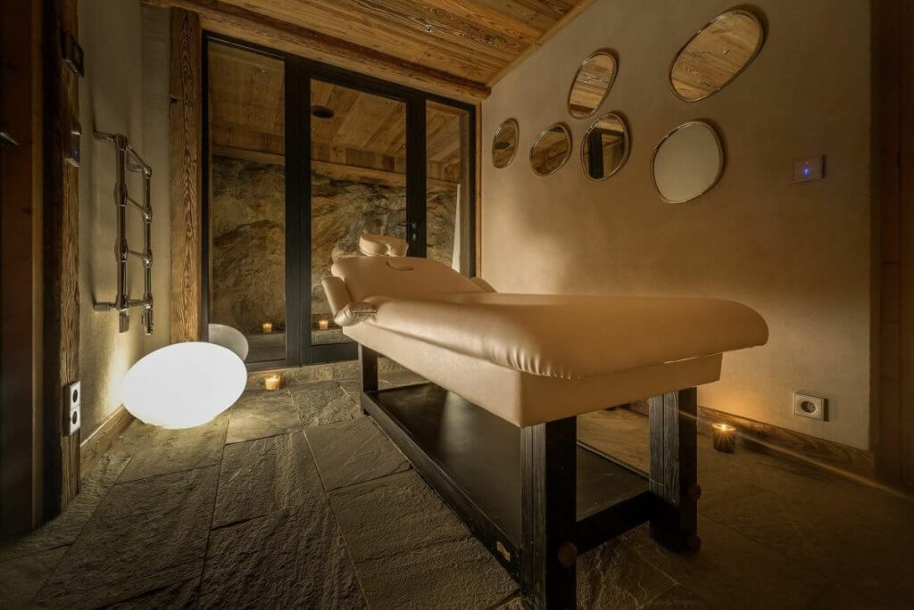 Luxury villa spa room at Chalet Husky with massage table, stone floors, warm lighting, and natural outdoor views.