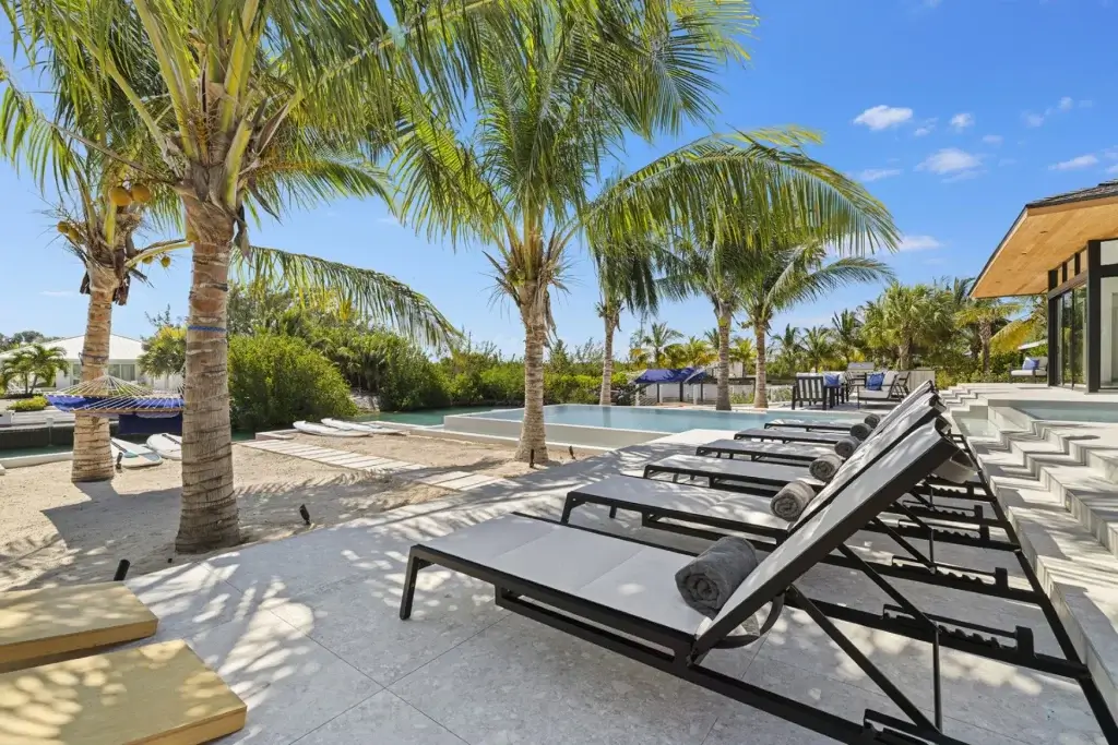 Canal-front terrace with private pool, shaded loungers, and tropical palm surroundings at Aqua Solis in Leeward