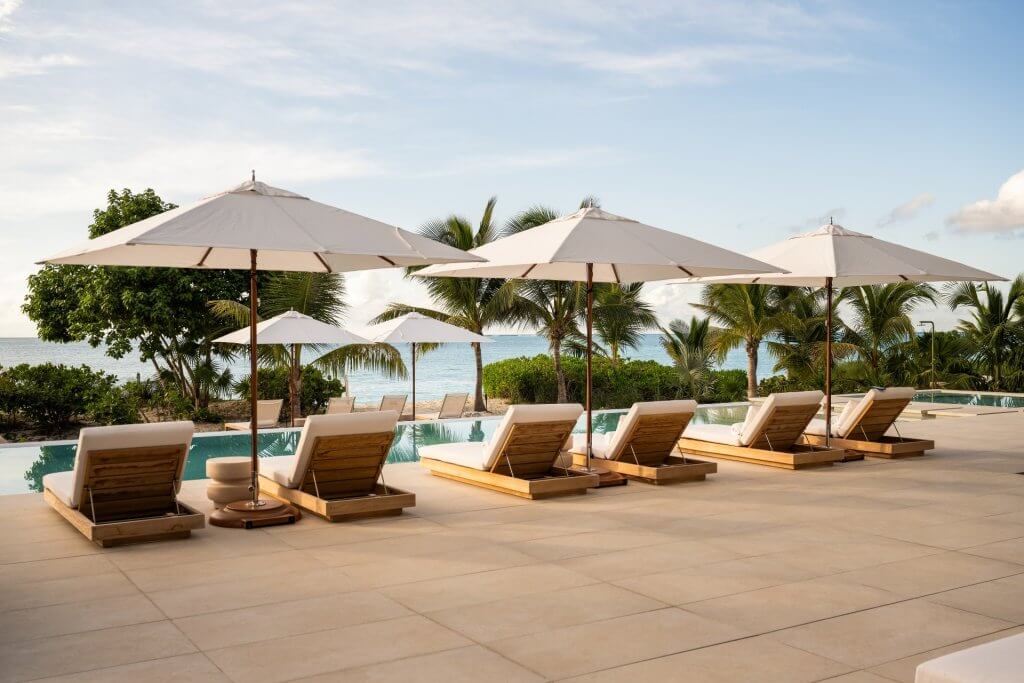 BE The Reserve Villa 2 pool terrace among luxury villas in Turks and Caicos, with shaded loungers and ocean views.