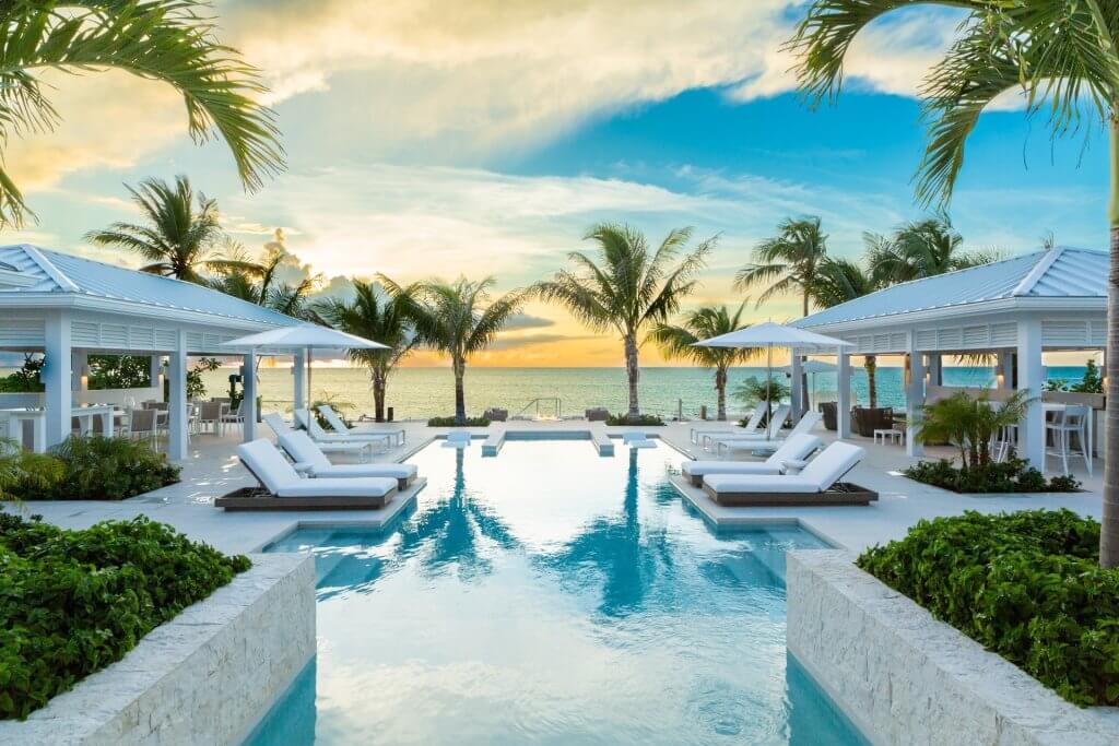 Milestone’s sunset infinity pool among luxury villas in Turks and Caicos, with ocean views and shaded lounges.