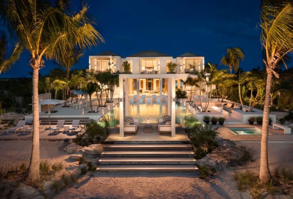 Emerald Pavilion, one of the best Caribbean villas, with an illuminated pool and palm-framed terrace at night.