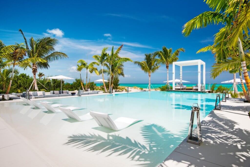 Emerald Pavilion’s private pool with submerged loungers, shaded seating and a palm-lined beachfront view.