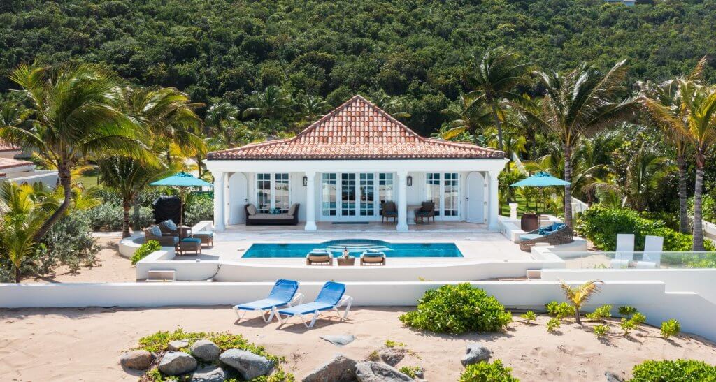Les Palmiers SXM in St Martin, with a private pool, palm-lined grounds, and beachfront loungers.