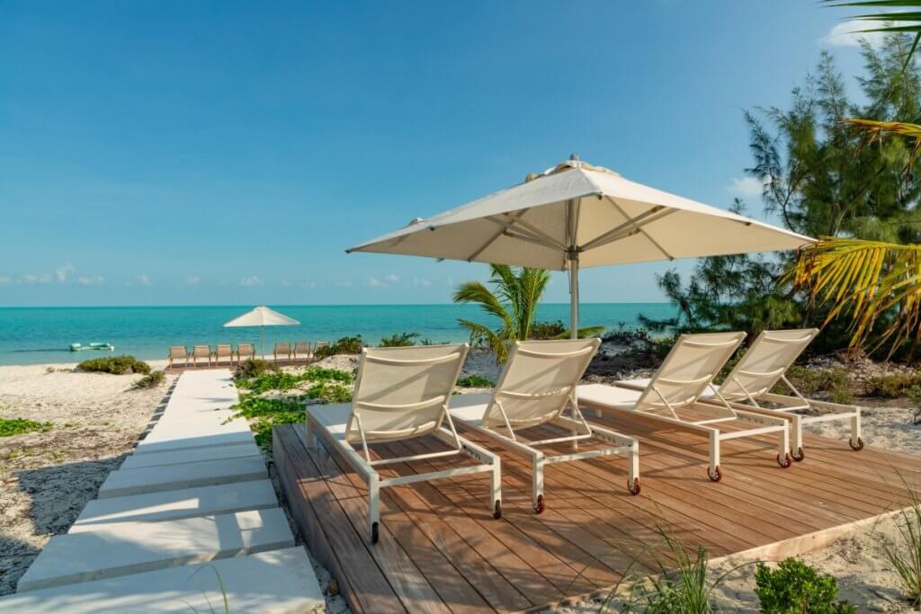 Dune House beach deck with loungers and ocean views among Long Bay Beach villas in Turks & Caicos.