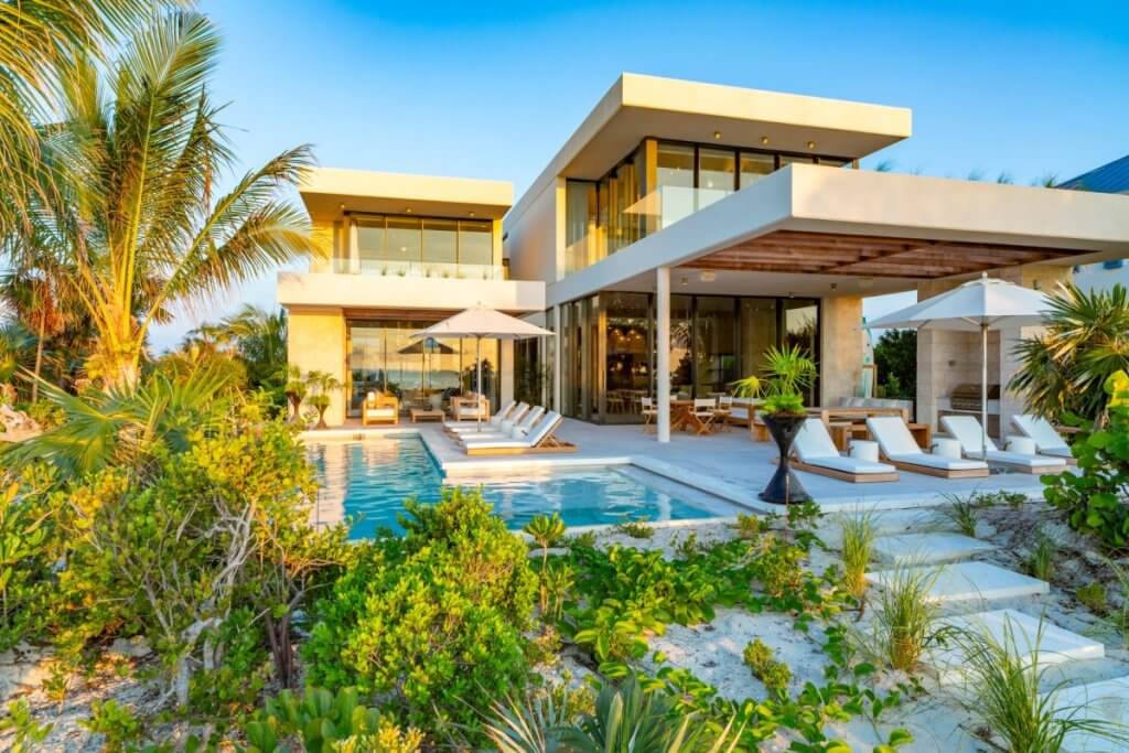 Dune House exterior with private pool, shaded terrace and tropical gardens among Long Bay Beach villas.