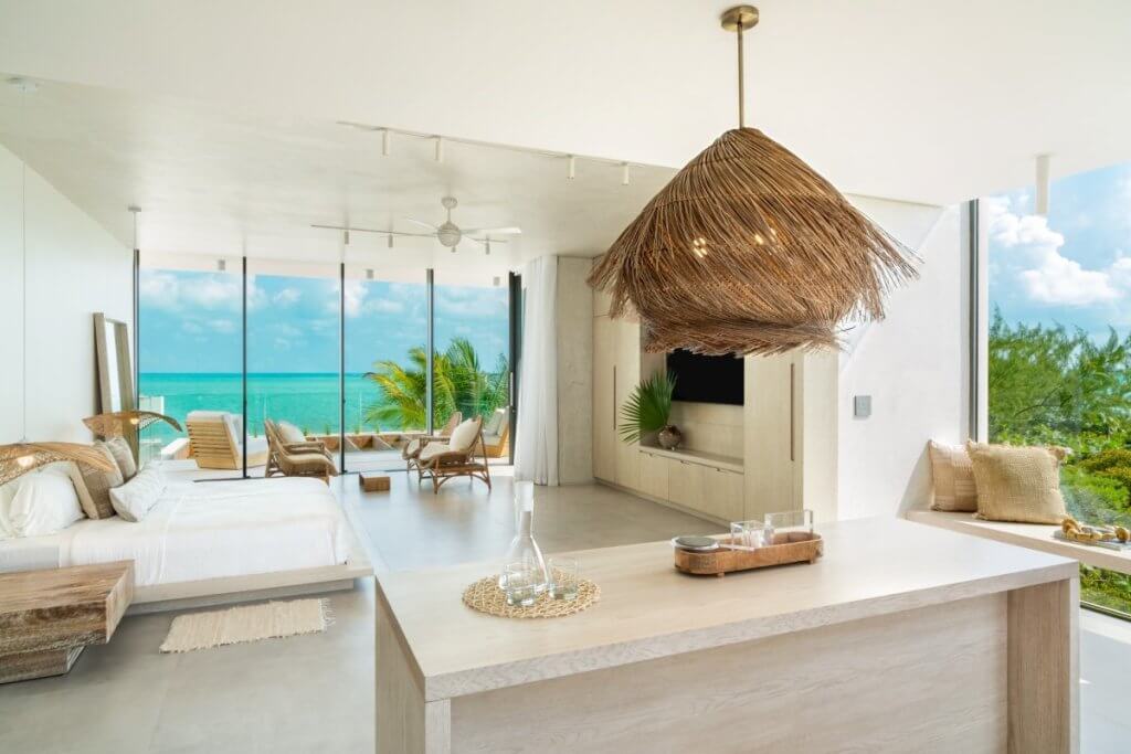 Ocean-view suite at Dune House with king bed and lounge seating among Long Bay Beach villas.